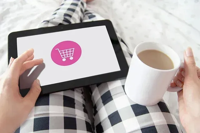 A photo framed on a person's lap with a coffee and tablet on her. She is buying online.